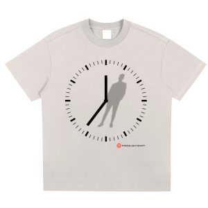 Beige t-shirt featuring a minimalistic black clock design with hour and minute hands forming a shadow of a standing figure, blending time and human presence. Includes the FromLight2Art logo at the bottom.